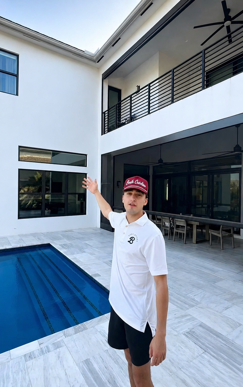 Boca Bright Wash team member in a white branded polo and cap, standing by the pool of a modern South Florida home he just finished cleaning.